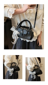 Detail of a black glossy shell bag with a white organza bow and pearl charm