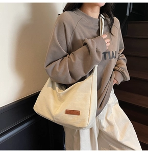Detailed shot of large cream canvas tote bag with brown leather logo patch on street style