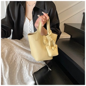 Detail of lychee pattern leather bucket bag in pale yellow with a matching mini coin purse