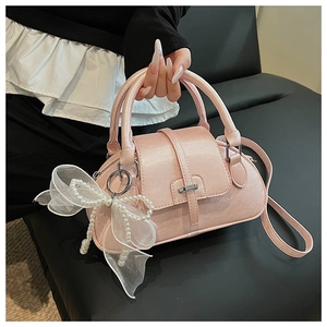 Detail view of pink shell bag with mesh bow, pearl strap and premium leather texture