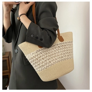 Detail of hollow woven straw tote bag with brown leather handles and geometric patterns