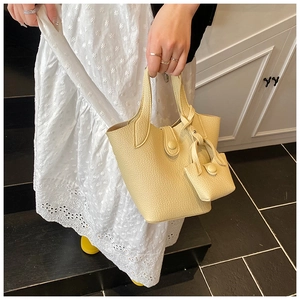 Detail of beige lychee grain leather bucket bag with matching mini charm pouch