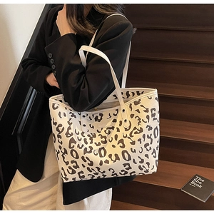 Macro-opname van grote tote bag met koeprint die textuur en leren hengsels toont