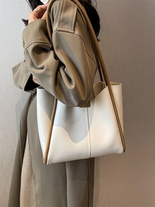 Minimalist beige contrast tote bag with brown handles worn by model in trench coat