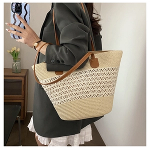 Detail of hand-woven straw tote bag with brown leather handles and hollow pattern