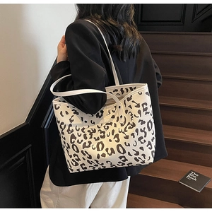 Detail van een grote tote bag met luipaardprint en dunne bandjes gedragen door een model