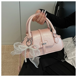 Close-up of pink shell handbag with a large white bow and elegant pearl charm detail