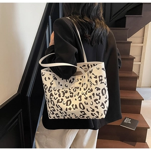 Detailopname van grote shopper met koeienprint, lange hengsels en ruime binnenkant