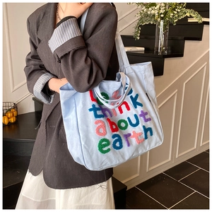 Detalle de bolso tote de lona azul claro con bordado de toalla colorido y eslogan eco