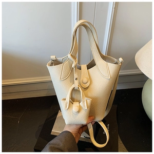 Detailed macro view of the cream-colored bucket bag featuring lychee grain texture and pouch