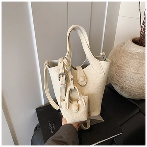 Detail of off-white bucket bag with lychee texture and matching mini charm bag
