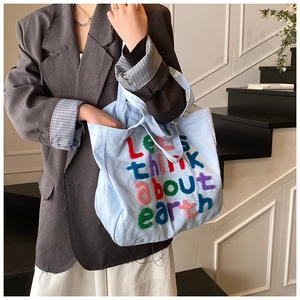 Detalle del bolso tote de lona azul claro con bordado multicolor en la parte delantera