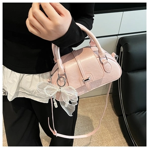 Close-up of pink glossy shell bag with white lace bow and pearl chain details