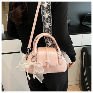 Detail view of pink bow shell bag featuring lace pearls and adjustable crossbody strap