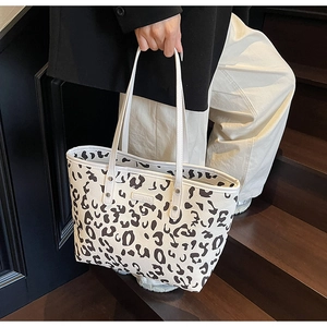 Detail van een leopard tote bag van wit kunstleer met slanke dubbele handvatten eraan