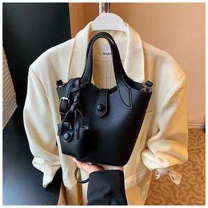 Detail of black lychee grain leather bucket bag with matching mini charm pendant