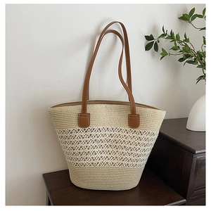 Detail of hollow mesh woven straw tote bag with brown leather handles on wooden cabinet