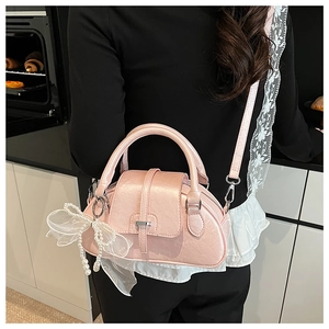 Rear view of a model wearing a pink pillow bag with decorative pearl bow in a kitchen
