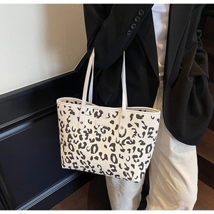 Detailopname van zwart-witte luipaardprint tote bag met klinknagels en dunne riemen