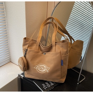 Détail du sac cabas en toile marron avec un petit porte-monnaie et logo brodé