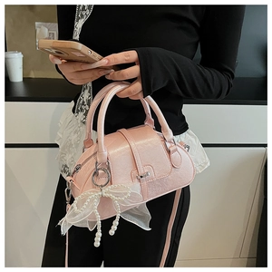 Detail of pink faux leather shell bag with pearl bow charm and detachable shoulder strap