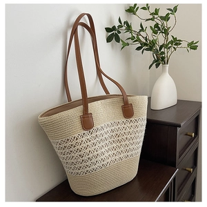 Detail of hollow straw weave and dark brown leather handles on large tote bag
