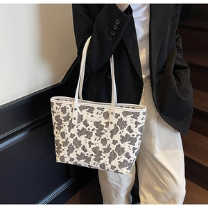 Grote shopper met koeienprint gedragen bij een zwarte blazer voor werkmode