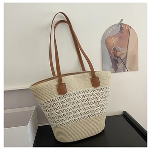 Detail of woven straw tote bag with bicolor layers and brown leather shoulder straps