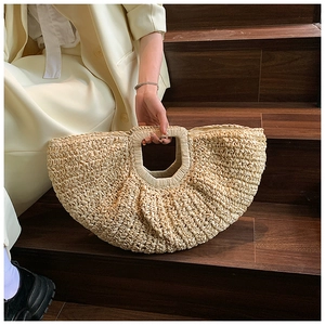 Detailed close-up of natural beige straw weave texture on a semi-circular beach tote bag