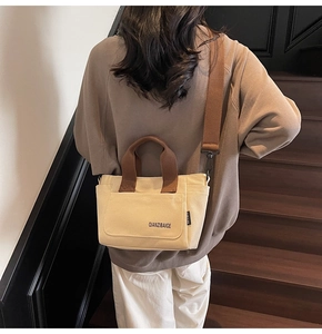 Detailopname van beige canvas draagtas met bruine riemen en merklogo-opdruk