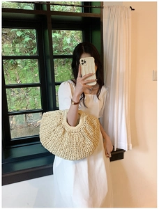 Detailed close-up of a large beige hand-woven straw tote bag with textured crochet patterns