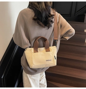 Detailopname van de canvas shopper met tweekleurige panelen in crème en bruin en voorvak