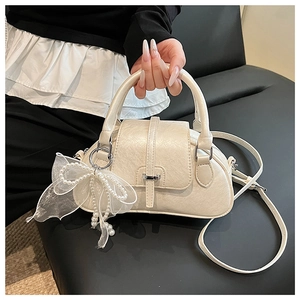 Detailed macro view of the cream shell bag with lace pearl bow charm and leather texture
