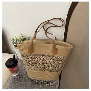 Detail of hand-woven straw tote with hollow patterns and brown leather handles