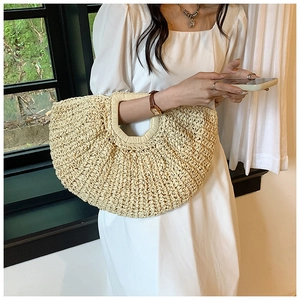 Detail of a beige woven straw handbag with a large capacity and elegant crescent shape