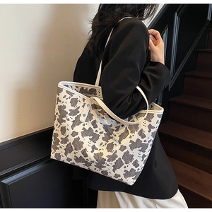 Detailweergave van een tote bag met koeprint, zwart-wit patroon en stevige handvatten