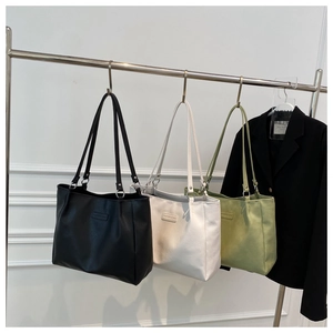 Detailed display of black, white and green tote bags in soft pebble grain leather texture