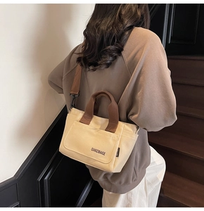 Detail van de crème canvas crossbodytas met bruine banden gedragen door een model