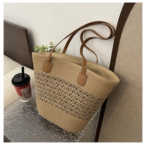 Detail of hollow woven straw tote with brown leather handles and a spacious interior