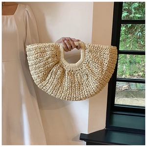 Detail of hand-woven half-moon straw bag with textured cream finish for summer beach style
