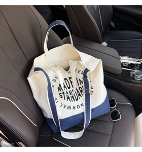 Détail du sac fourre-tout en toile avec imprimé et bandoulière bleue sur siège auto