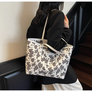 Detailweergave van de grote draagtas met koeienprint getoond op een model voor werk