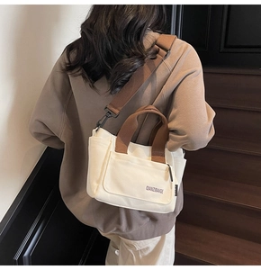 Detail van de gebroken witte canvas shopper met bruine schouderriem en voorvak met klep