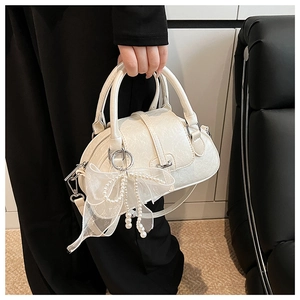 Detail of cream shell bag with organza bow, pearl charms and silver zipper