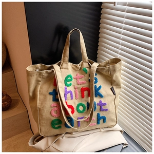 Primer plano detallado del bordado de felpa de colores en el bolso tote de lona caqui