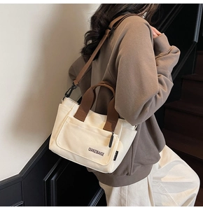 Detailaanzicht van de canvas crossbodytas met meerdere vakken en bruine banden