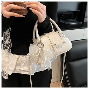 Detail of cream shell bag with pleated texture, lace bow and pearl charm pendant