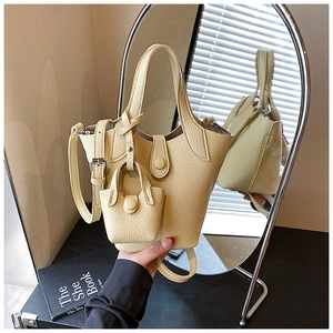 Detail of lychee textured bucket bag in cream with matching mini charm and mirror reflection