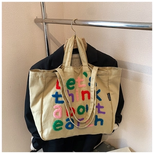 Detalle del bolso tote de lona con bordado colorido let's think about earth