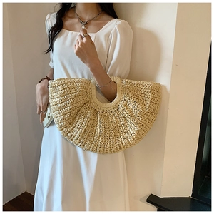 Close-up of beige straw woven tote bag featuring a hollow handle and fine flat weave texture